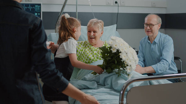 Old patient receiving visit from child and mother in hospital ward