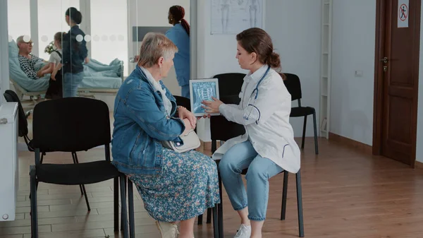 Doctor showing radiography scan on tablet to old patient — Stockfoto