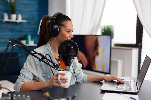 Vrouw vlogger holding cup en streaming podcast met behulp van laptop. — Stockfoto