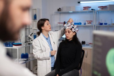 Nörolog doktor hasta başındaki beyin taramasını ayarlıyor.