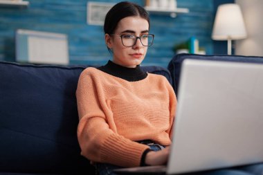 Kanepede dizüstü bilgisayar tutan programcı. Yazma kodu..