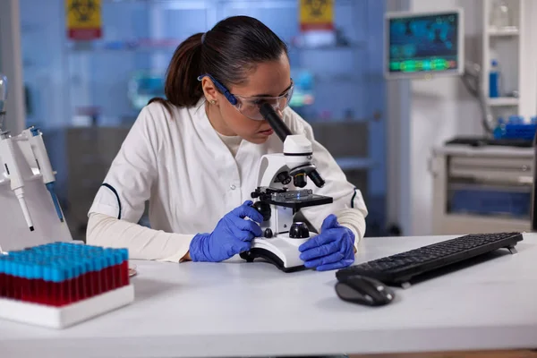 Specialist researcher analyzing blood sample under microscope — Stock Photo, Image