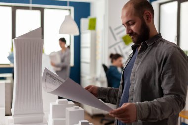 Gökdelen maketinin yanındaki konut projesinin taslağını okuyan mimar