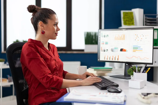 Administrador de inicio en camisa roja mirando gráficos en el monitor de la computadora. —  Fotos de Stock