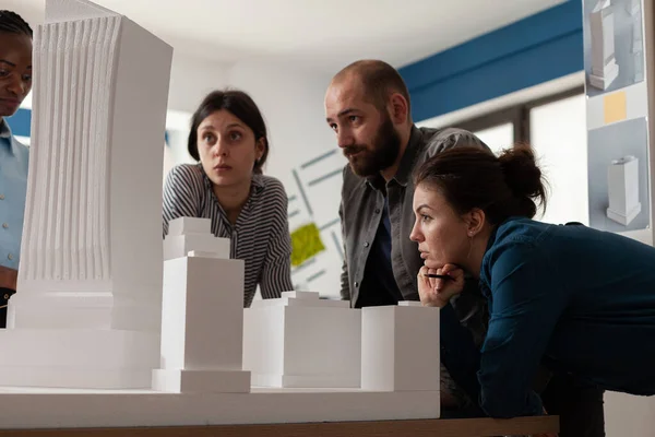 Team of professional architects looking at skyscraper maquette in architectural office — Stockfoto