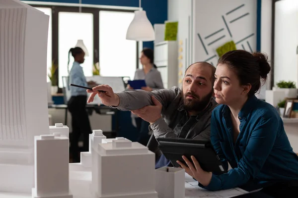 Arkitekt pekar penna på skyskrapa arkitektonisk modell samarbetar med kollega ingenjör — Stockfoto