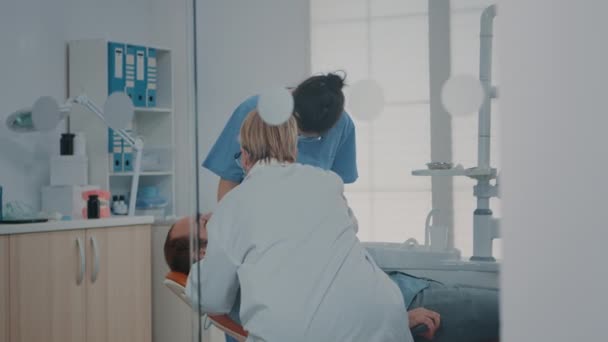 Medic and nurse examining teeth after oral care procedure — Video Stock