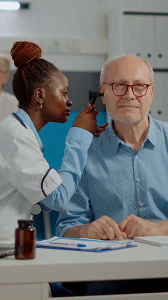 Африканський лікар - американець, користуючись отоскопом, який консультує старшого чоловіка — стокове фото