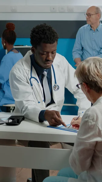 Adulte travaillant comme médecin en manteau blanc parlant à un vieux patient — Photo