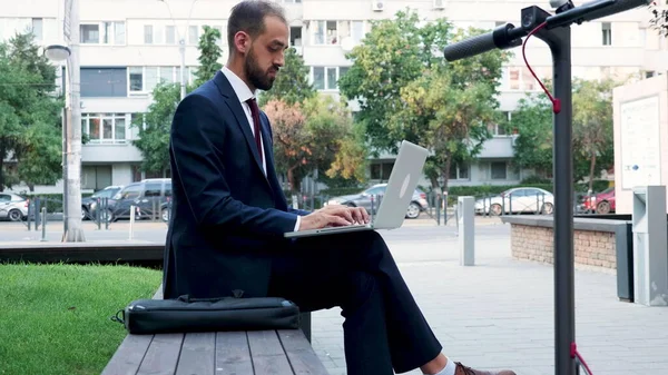 商人拿着笔记本电脑坐在创业公司办公室前的长椅上 — 图库照片