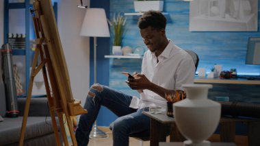 Siyah ressam güzel resimler için akıllı telefon kullanıyor.