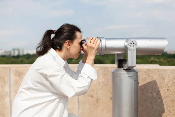 Молодая туристка смотрит в бинокль в телескоп — стоковое фото