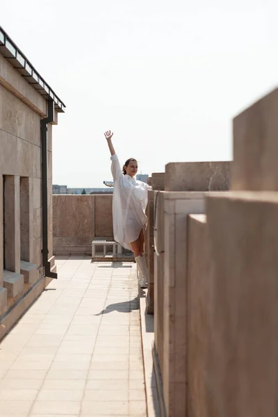 Heureuse femme touriste levant la main tout en se tenant sur le toit de la tour bénéficiant d'une vue panoramique — Photo