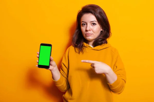 Persona que sostiene el teléfono móvil con pantalla verde vertical — Foto de Stock