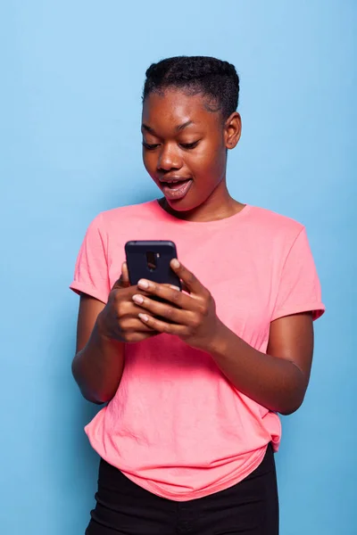 Retrato de una joven afroamericana sosteniendo mensajes de teléfonos inteligentes con un amigo — Foto de Stock