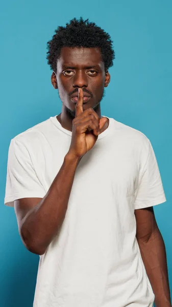 Young man doing silence gesture with finger on mouth — Stock Photo, Image