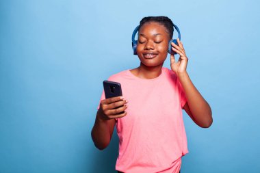 Kulaklık takan gülümseyen Afrikalı Amerikalı genç bir kadının portresi.