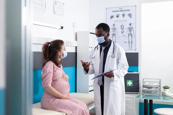 Doctor showing checkup files to pregnant woman — Fotografia de Stock