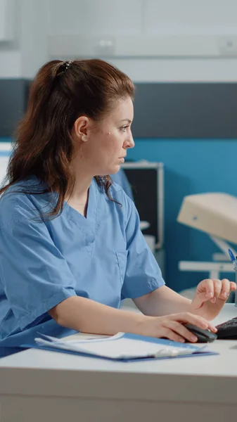 Medizinische Assistentin arbeitet am Computer mit Patienteninformationen — Stockfoto