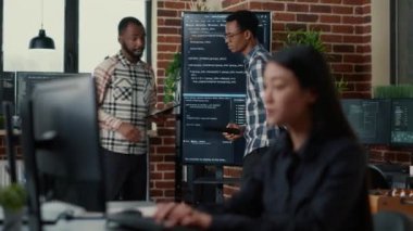 Programmers leaving after analyzing source code on wall screen tv comparing errors using digital tablet