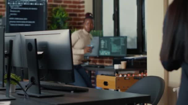 Two software developers coming at desk and sitting down holding laptop with coding interface — Wideo stockowe
