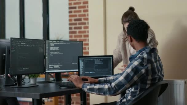 Two programmers doing high five hand gesture at desk with multiple screens running code celebrating — стоковое видео