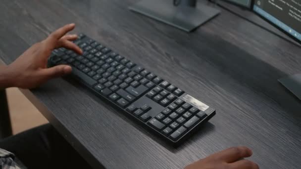 Gros plan de programmeur afro-américain mains dactylographiant le code sur le clavier tout en regardant les écrans d'ordinateur — Video
