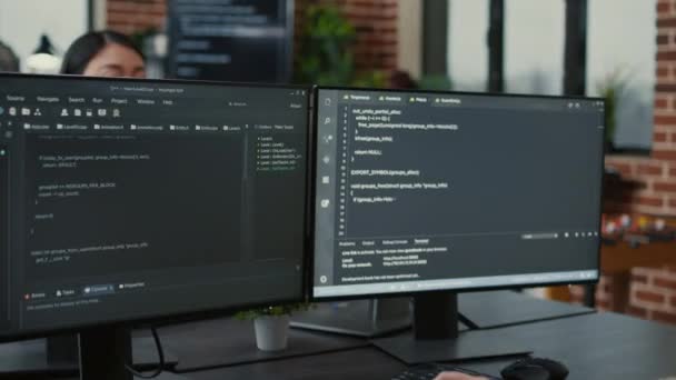 Focused software developer writing code looking at multiple computer screens — Vídeo de Stock