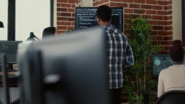 Team of coders analyzing code on wall screen tv comparing errors using digital tablet