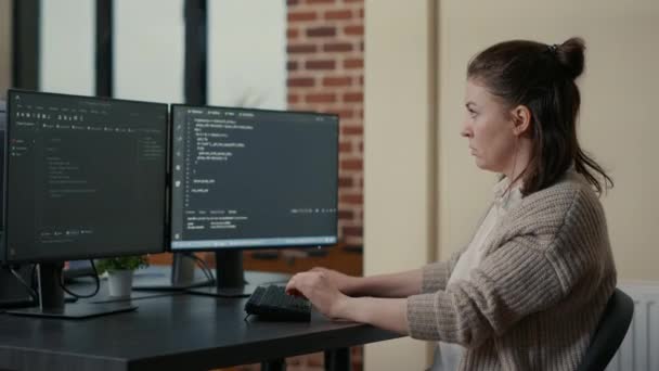 Portrait of focused programer writing code looking at multiple computer screens — Stok Video