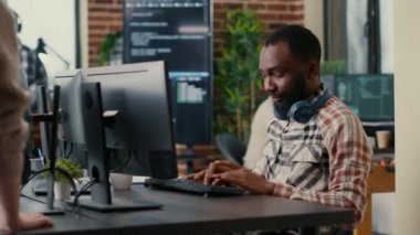 Relaxed software developer wearing wireless headphones smiling working looking at computer screen
