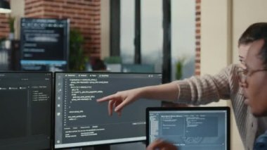 Programmer analyzing compiling code on multiple screens takes off glasses and doing high five hand gesture