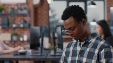 Portrait of programer sitting down looking at laptop screen and looking up smiling at camera