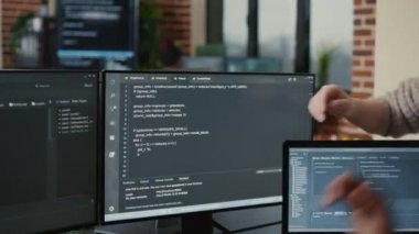 Software developer looking at running code on multiple screens takes off glasses and doing high five hand gesture