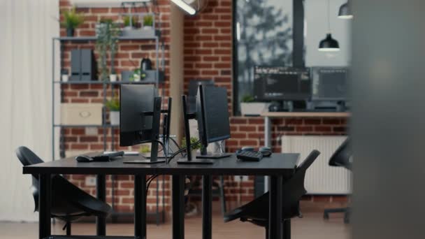 Computer screens on desk in empty data room and computers in background running programming code — Stock Video