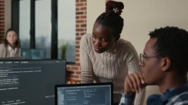 App developer removing glasses while explaining algorithm to colleague programer