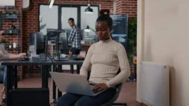 Afro-Amerikan programcının portresi dizüstü bilgisayarda oturmuş gülümsüyor.