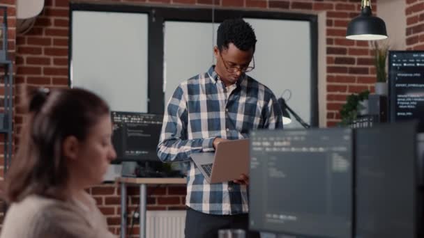 Πορτρέτο του Αφροαμερικανού προγραμματιστή λογισμικού που κρατά φορητό υπολογιστή κοιτάζοντας ψηλά και χαμογελώντας — Αρχείο Βίντεο