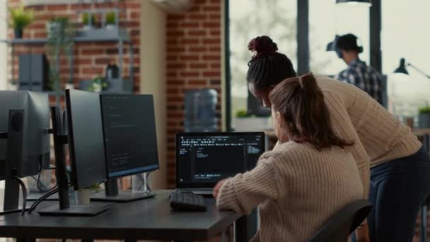 Два системных инженера анализируют исходный код на ноутбуке в поисках ошибок на экране — стоковое видео