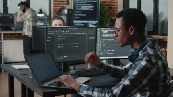 Портрет програміста, який фіксує окуляри під час введення тексту на ноутбуці, задоволений результатами компіляції, що сидять за столом — стокове відео