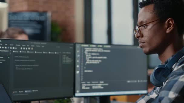 Portrait of focused software developer writing code arranging glasses sitting at desk — стоковое видео