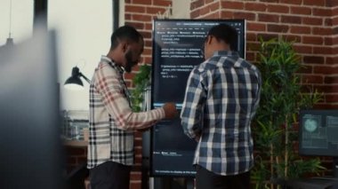 Yazılım programcılarından oluşan bir ekip, duvar ekranındaki kaynak kodu inceledikten sonra ayrılıyor