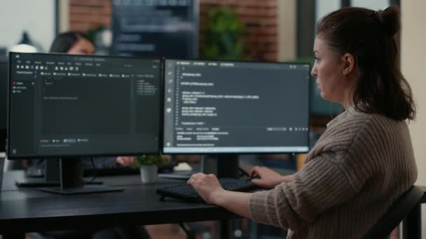 Junior programer sitting down on desk showing laptop with source code to senior dev — Video Stock