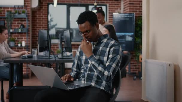 Portrait of african american programer sitting down working on laptop arranging glasses — Vídeo de Stock