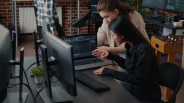 Two software engineers analyzing source code running on laptop screen looking for errors