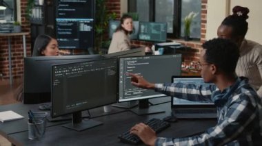 Yapay zeka bulut programcılarından oluşan karma bir ekip birden fazla ekranın önünde programlama hakkında konuşuyor.