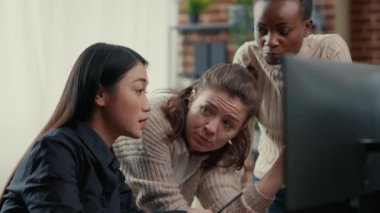 Software engineer pointing at computer screen explaining running code to coworkers brainstorming software ideas