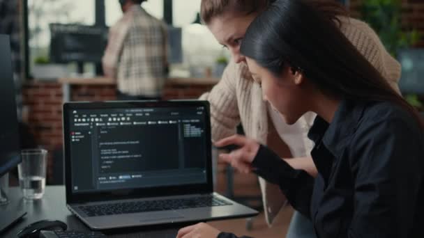 Team of software developers talking about source code running on laptop screen — стоковое видео