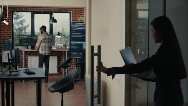 Programer holding laptop with coding interface entering software development agency office — Stock videók