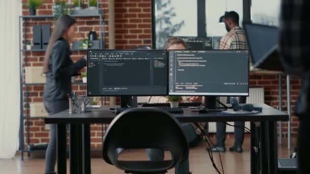 コードを解析するコンピューター画面を備えたデスクに座っているラップトップ上のプログラマーのコーディング — ストック動画